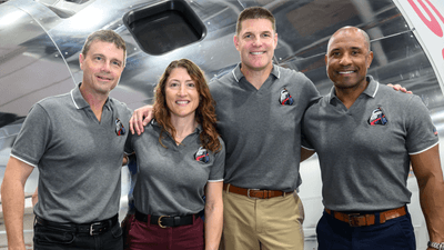 the four of them standing in front of the orion spacecraft.