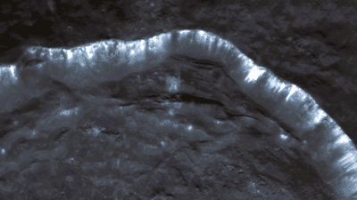 Portion of a crater rim is visible with many bright lines streaking down
