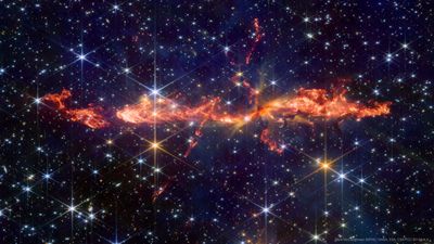 the background of the image is filled with stars. In the center a large, mostly stright jet that looks like flames is visible. smaller jets criss cross this one.