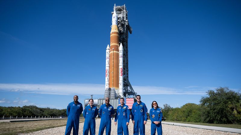 NASA astronaut Andre Douglas and CSA (Canadian Space Agency) astronaut Jenni Gibbons and prime crewmembers NASA astronauts Victor Glover, Reid Wiseman, CSA (Canadian Space Agency) astronaut Jeremy Hansen, and NASA astronaut Christina Koch, pose for a picture with NASA’s Space Launch System (SLS) rocket and Orion spacecraft,