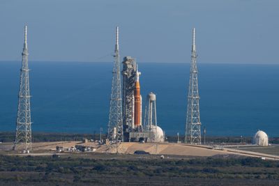 A picture from the distance showing the rocket and the other structures around the launch pad. Behind is the ocean.