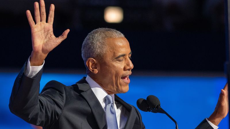 Obama at the podium of the democratic convention raising his hands while speaking