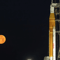 the rocket on the launchpad with the rising full moon behind. 