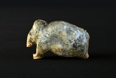 A prehistoric mammoth sculpture with ancient script