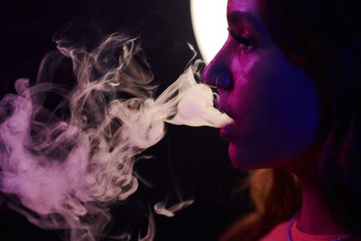 A woman breathing out vapour smoke 