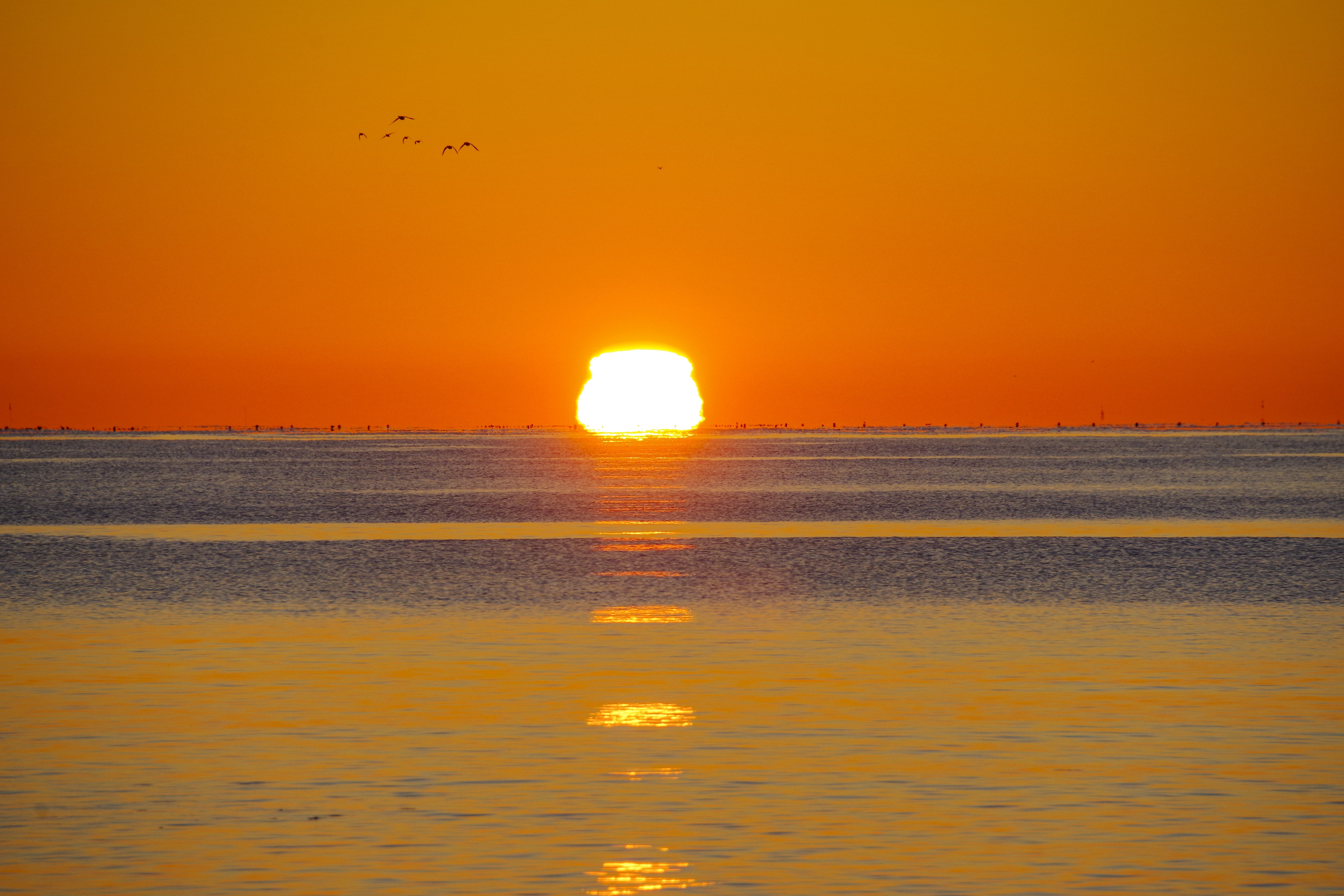 The Sun is actually below the horizon behind the sea but the atmosphere's refracts the light creating an illusion that shows it above the horizon. The Sun is actually below the horizon behind the sea but the atmosphere's refracts the light creating an illusion that shows it above the horizon.