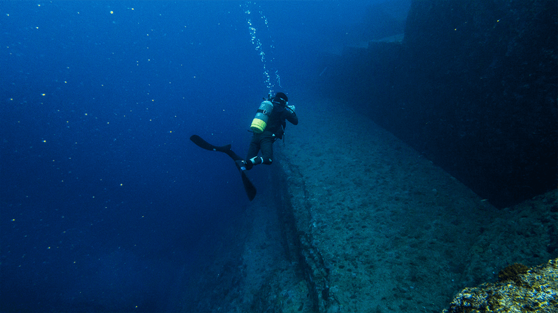 A diver at Yonaguni Monument. Rocks resembling steps underneath the sea.