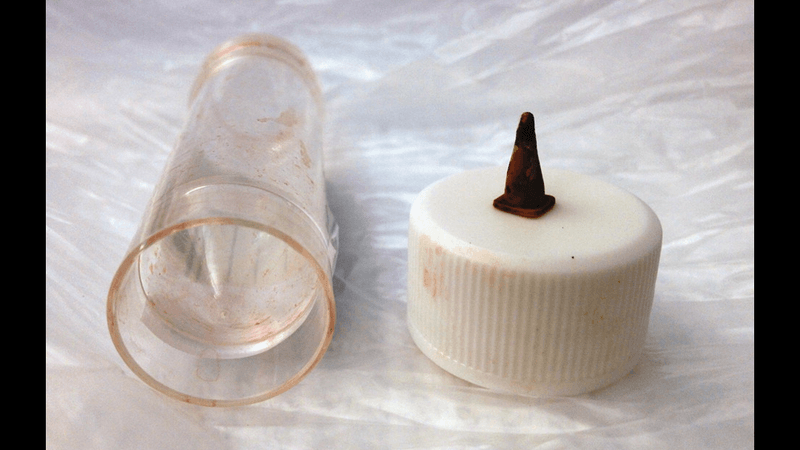 Image of the extracted toy traffic cone post operatively next to a specimen pot