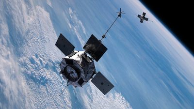 Two spacecraft are seen above the earth. They are boxy with solar panels arranged in a cross like shape.