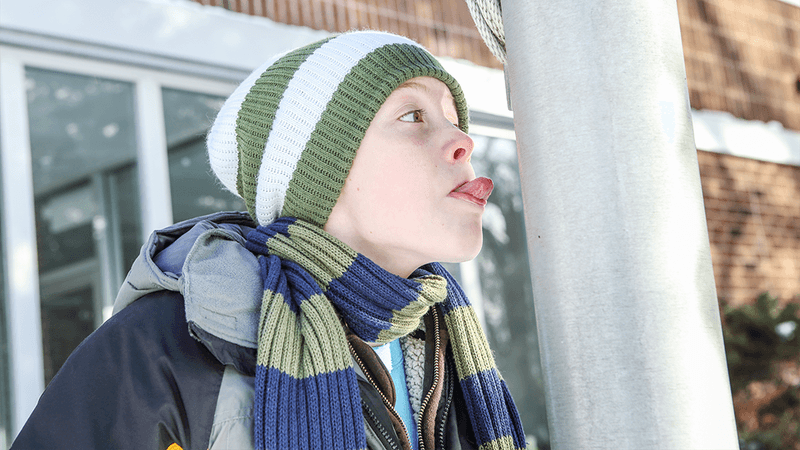 A boy about to stick his tongue to a frozen lamppost.