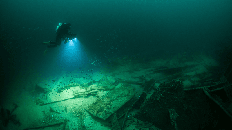 A diver looking at debris on the ocean floor.