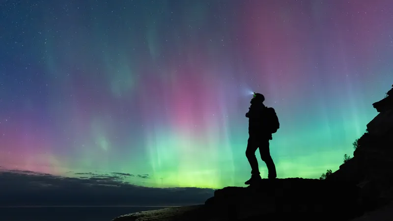A hoker lookin at the sky filled with aurorae