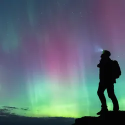 A hoker lookin at the sky filled with aurorae