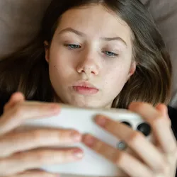 A girl, young teenager, on a smartphone looking at social media.