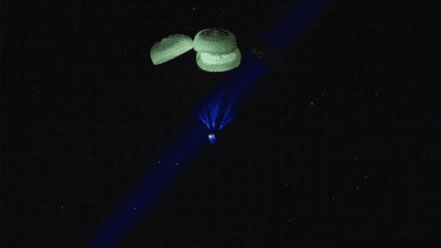 A crew of astronauts returning to Earth via parachute.