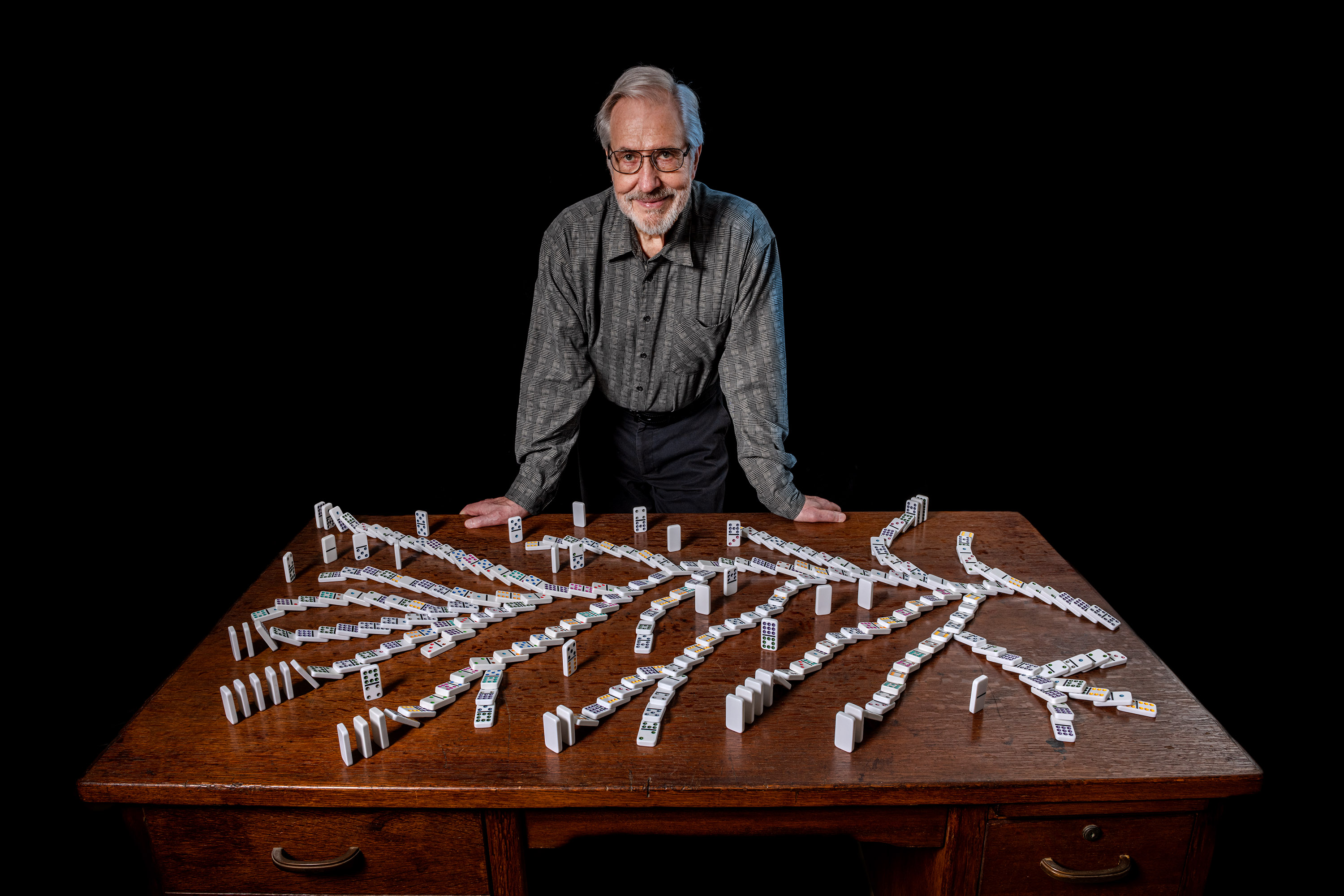 Kessler standing in front of a table where dominos are seen falling in a tree pattern