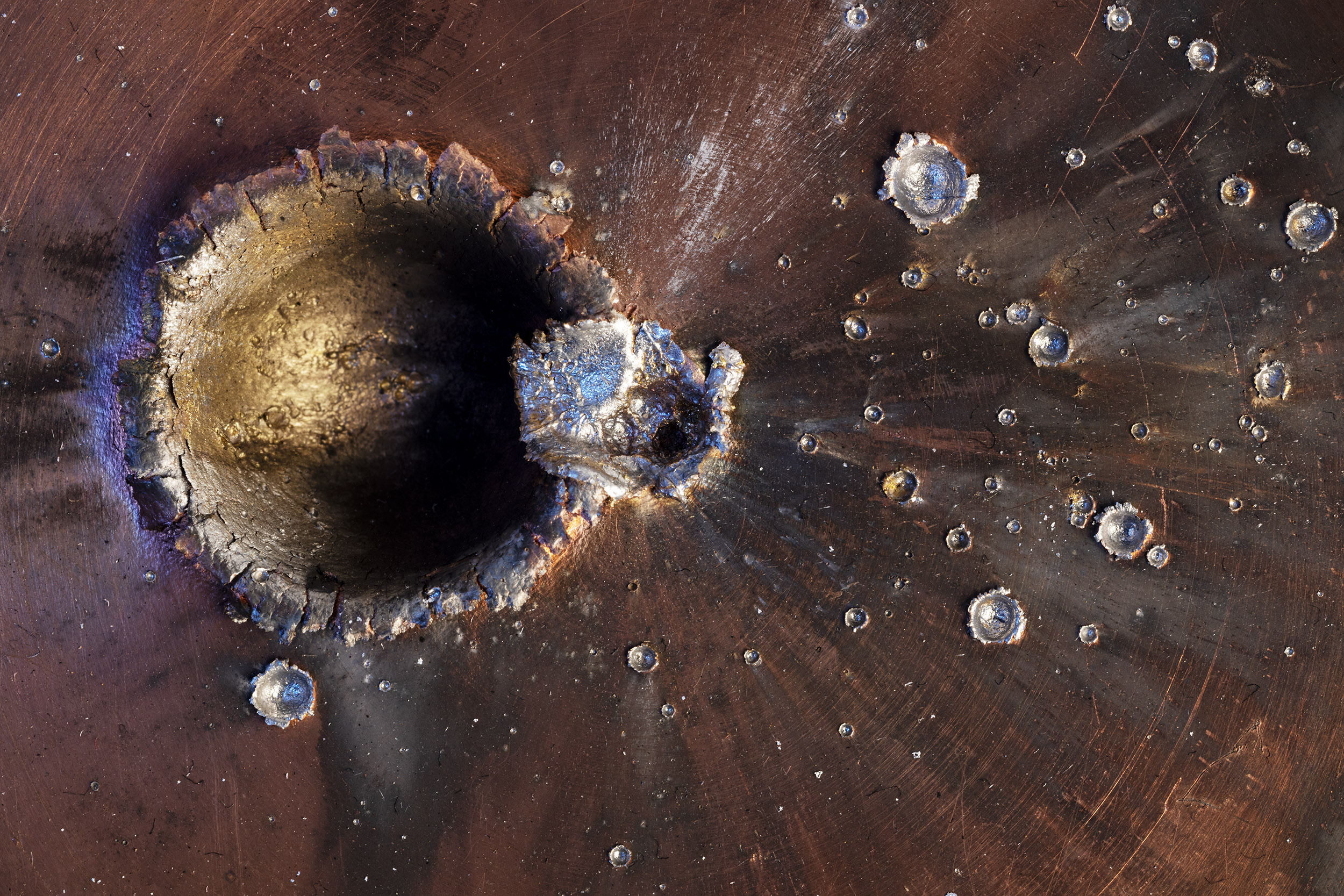 a circular hole and smaller holes in a block of metal look like craters on a planet