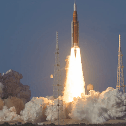 The rocket is see producing fire and vapor as it passes the launch pad tower.