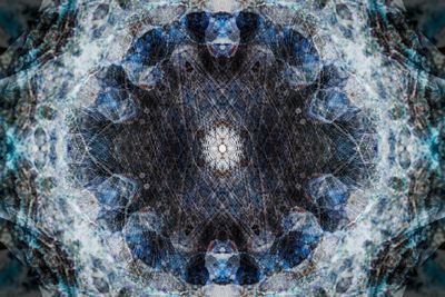 A kaleidoscopic pattern made up of a light outer ring of overlapping shades giving way to a bluer ring and then a central circle with a white circular pattern in the middle. 