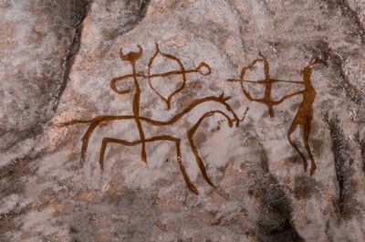 Prehistoric cave painting showing bow and arrow