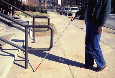 A blind person using a stick to walk.