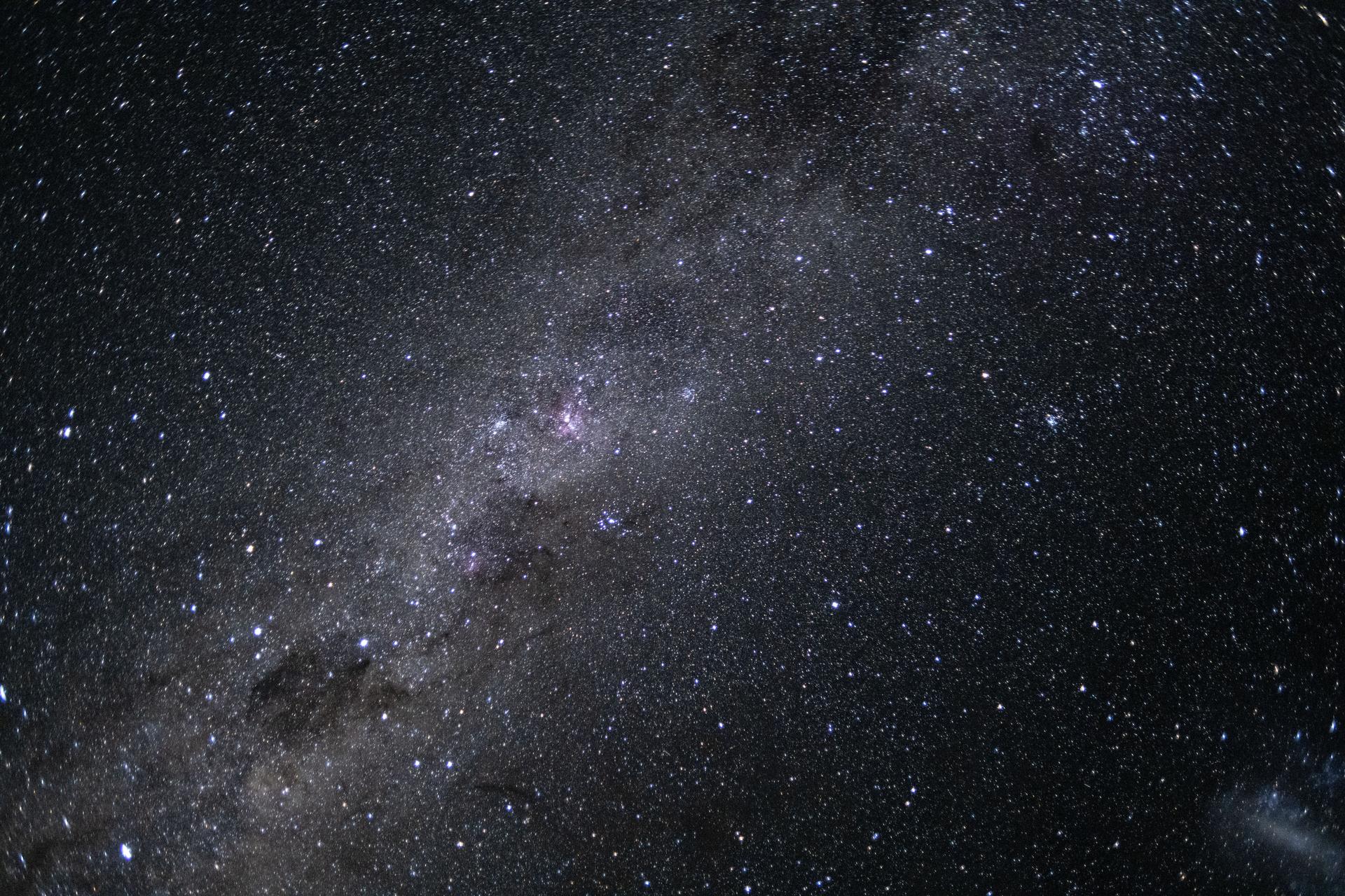 The Milky Way with sprial arms and surrounded by lots of other stars and space features.