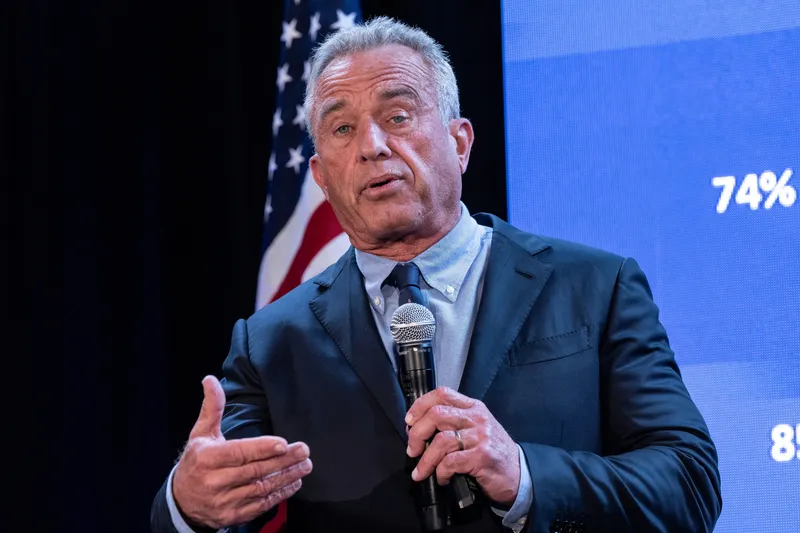 Robert F Kennedy Jr pictured speaking on stage with a microphone in his hand.