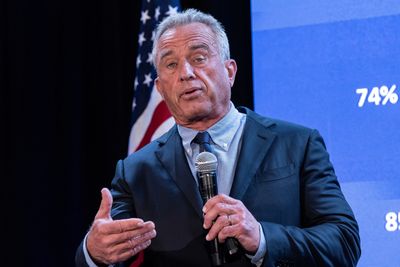 Robert F Kennedy Jr pictured speaking on stage with a microphone in his hand.