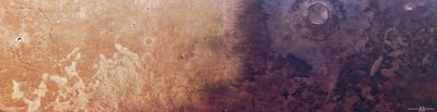 A wide view of the Martian surface seen from above. The landscape is split into two contrasting halves: the left side is lighter, sandy beige with faint ridges and cracks, while the right side is darker, reddish-brown and more heavily cratered. The boundary between the two regions is uneven and gradual, creating a striking colour contrast across the scene.