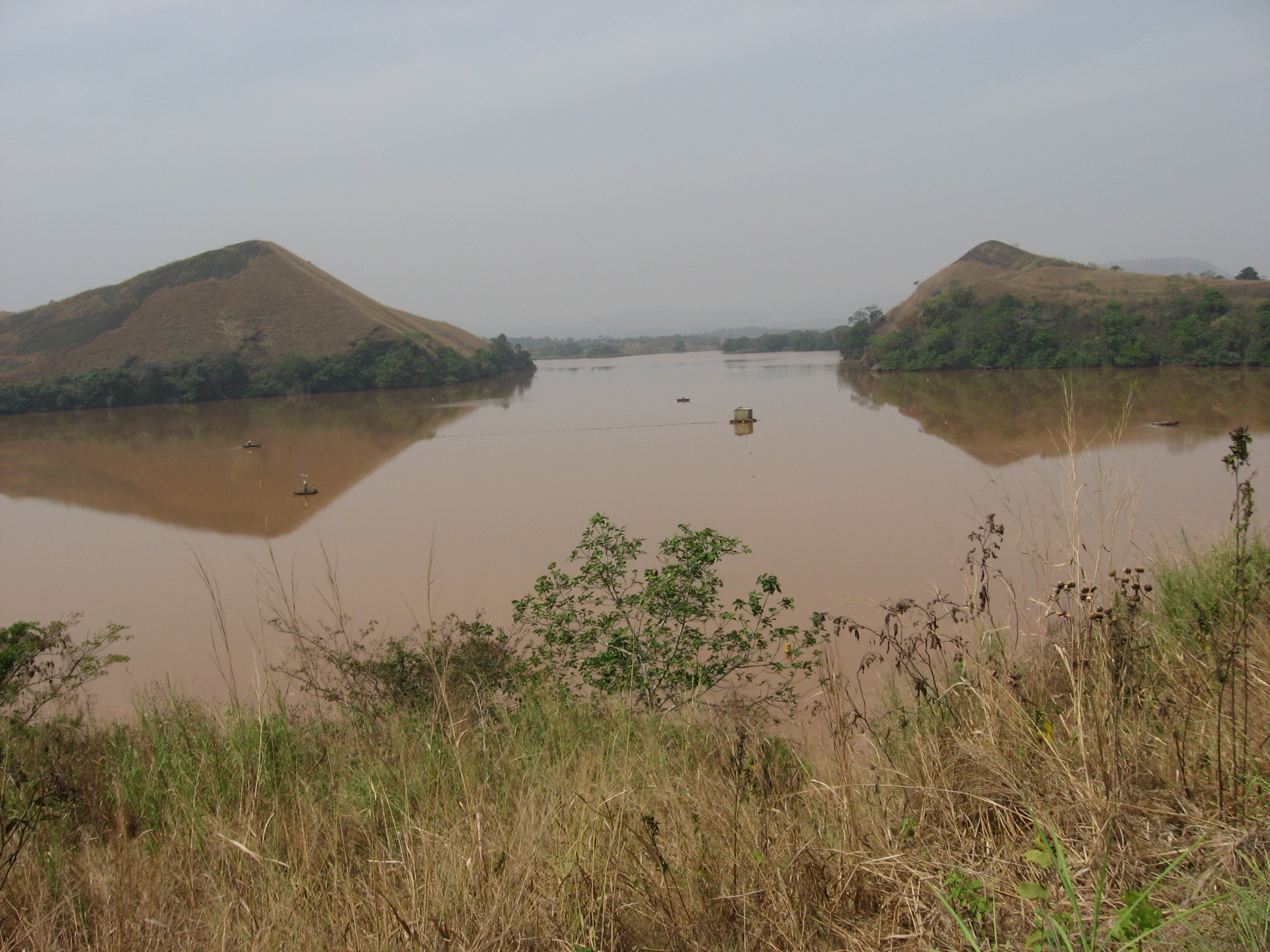 photo of lake taken from the bank with shrubs and grass in the foreground and two promontories in the middle distance