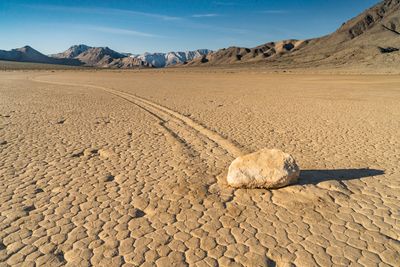 Vast playa, with a rock that has left a trail in the dried mud