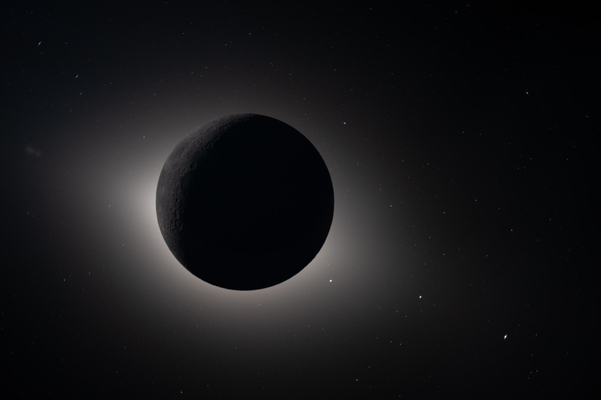 the moon blocking the Sun glowing back lit. Stars and planet are visible as bright dots around the Moon the moon blocking the Sun glowing back lit. Stars and planet are visible as bright dots around the Moon