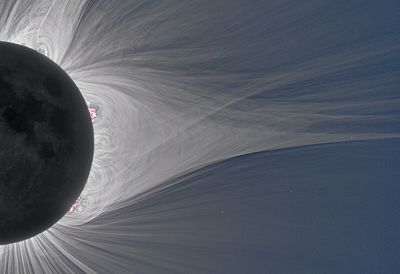 the moon is in front of the sun and around it there are many features which start wide and bulbous near the sun and become very thin as they move away.