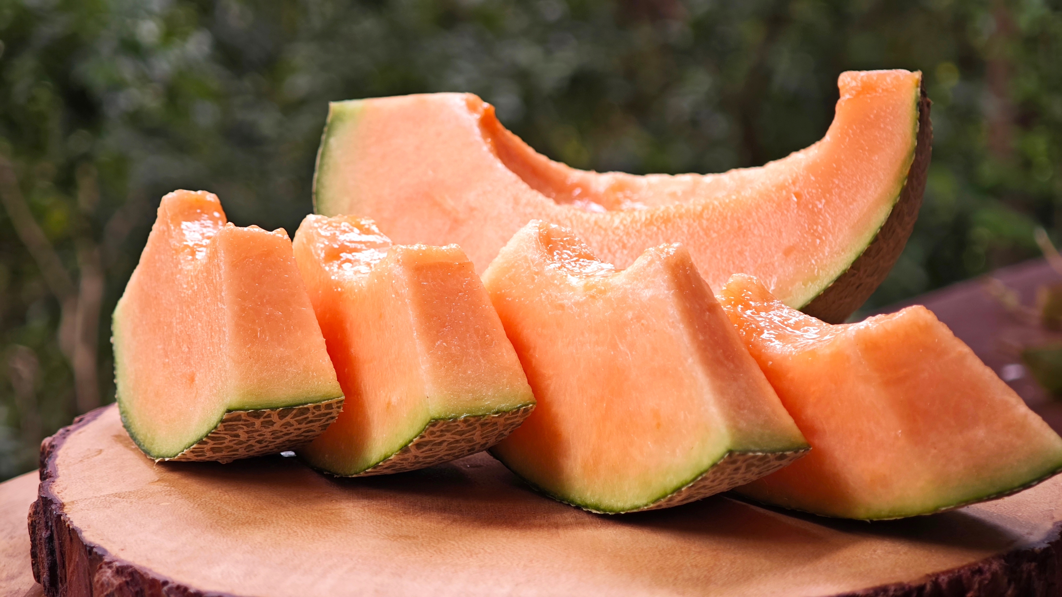 slices of cut cantaloupe on a wooden board slices of cut cantaloupe on a wooden board