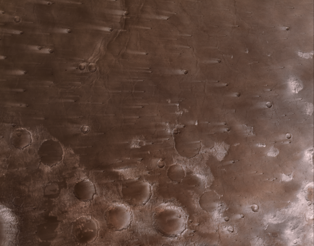 several tiny craters and some large ones with long streaks created by the wind