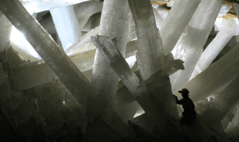 The silhouette of a human is dwarfed by the towering crystals.