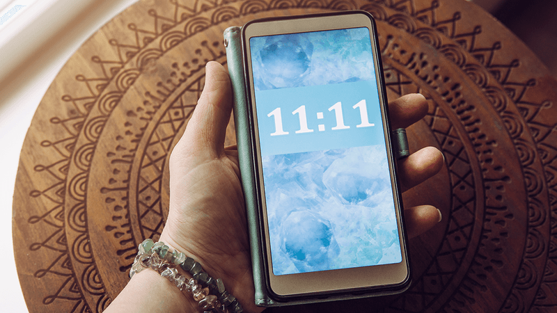 A hand holding a phone. The time reads "11:11".