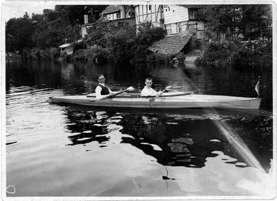 Oskar Speck and a boy onboard a folding kayak in a river.