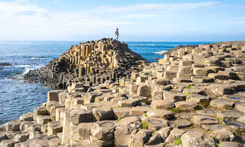 A person explores the Giant's Causeway, a unique geological formation in Northern Ireland.