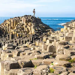 A person explores the Giant's Causeway, a unique geological formation in Northern Ireland.