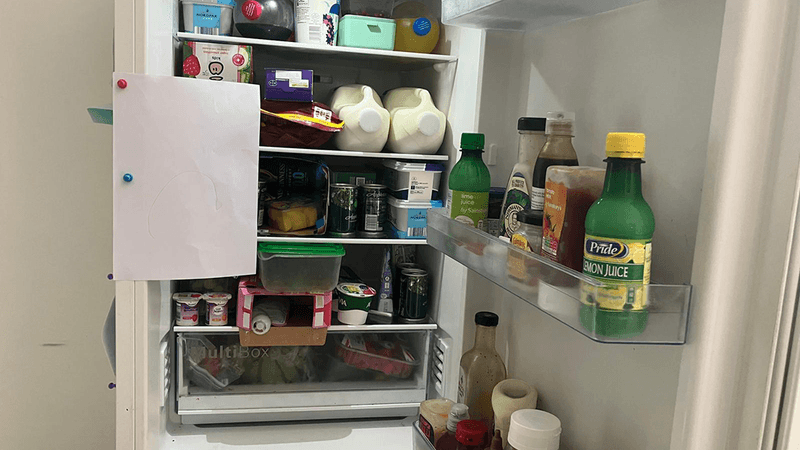 An open fridge, with a piece of A4 paper stuck to the side of it.