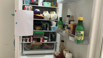 An open fridge, with a piece of A4 paper stuck to the side of it.