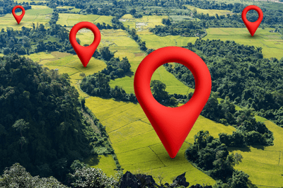 Aerial view of rice fields and forest with red location pin icons. Concept of GPS navigation, map positioning, digital tracking, land management, agriculture, and geographic location services