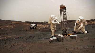 A digital image showing two astronauts on Mars. They erecting a small device and fastening to the ground. The astronaut on the right is kneeling. There are three silver boxes in front of them and, in the background, a shuttle is visible. 