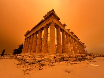 The skies above the Parthenon in Athens, Greece, glows a vibrant orange due to Saharan dust in the atmosphere.