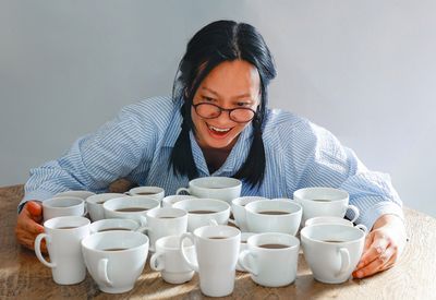 woman looking excitedly at lots of cups of coffee on a table in front of her