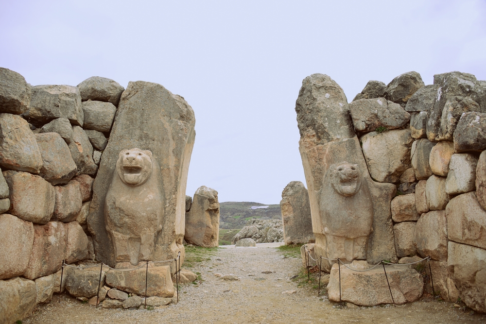 Crumbling stone ruins showing an entrance with two pillars with lion-like cats carved into them Crumbling stone ruins showing an entrance with two pillars with lion-like cats carved into them