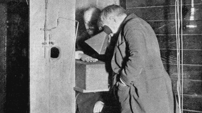 Thomas Edison looking through a calcium tungstate flouroscope at an assistant's hands.