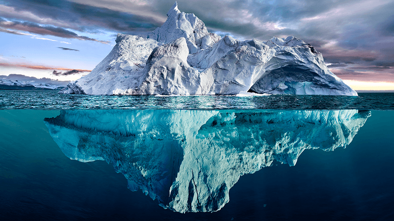 A large iceberg, which can be seen above and reflected in the water.