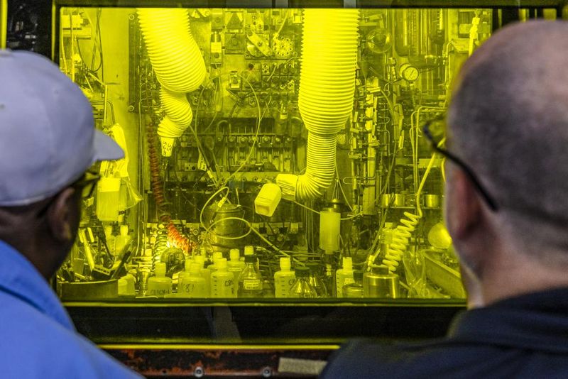 Technicians look into a hot cell in the Radiochemical Engineering Development Center where Cf-252 is produced.